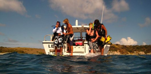 a group of people riding on the back of a boat in the water